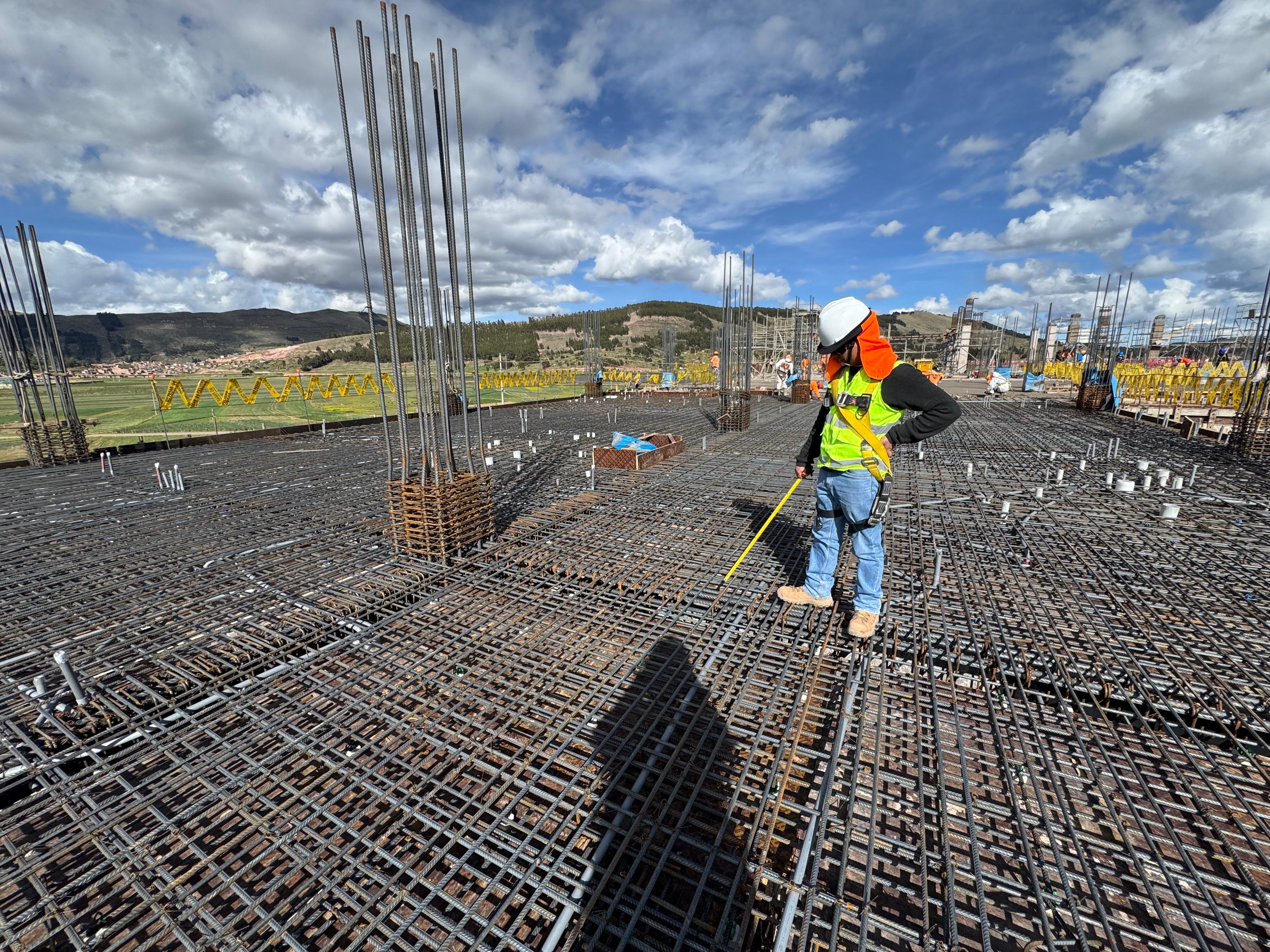 Ingeniero verificando con wincha el armado de acero de una losa de cimentación, en obra.