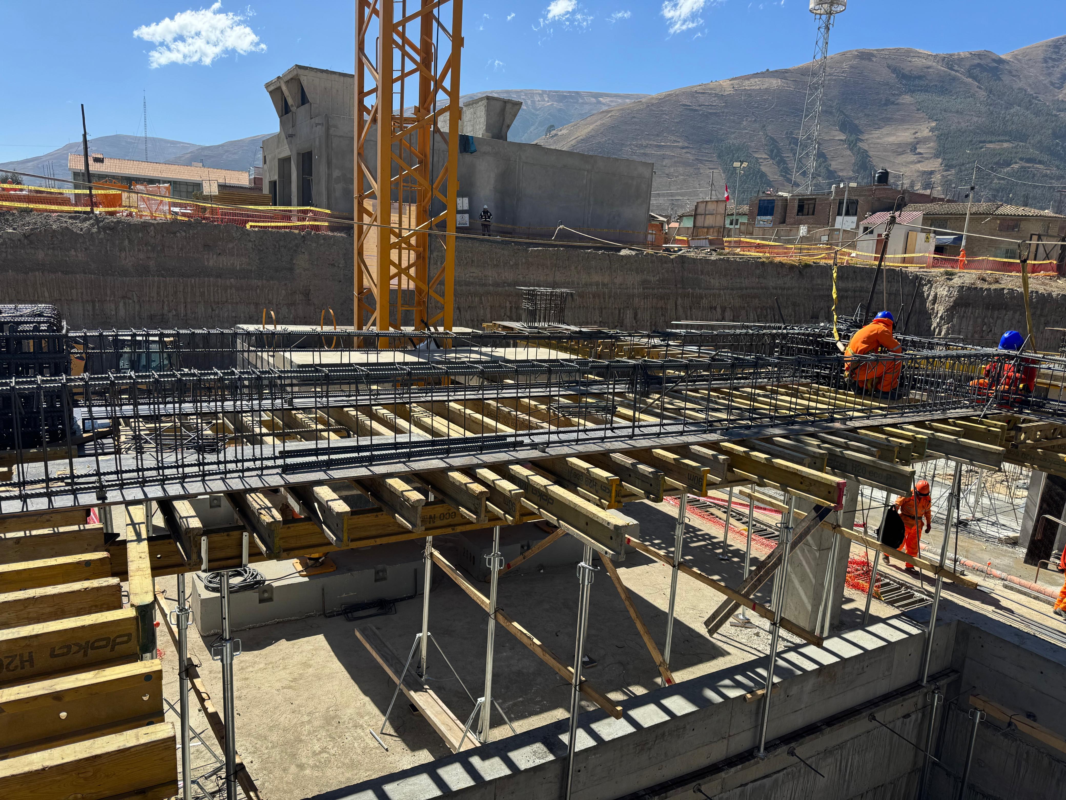 Armado de acero de las vigas de transferencia de un hospital en construcción, con encofrado y cerros al fondo.